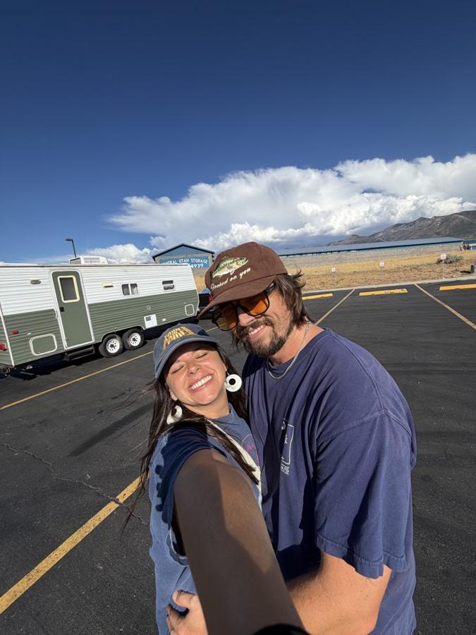 Ali and Sig hugging beside the green trailer under a big blue sky