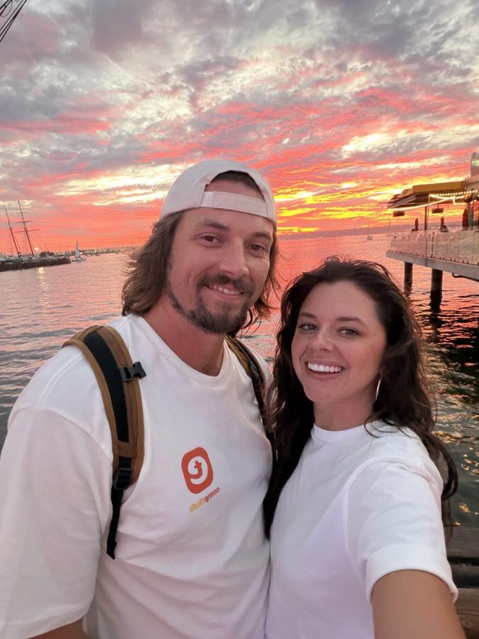 Ali and Sig on a pier at a pink and orange sunset