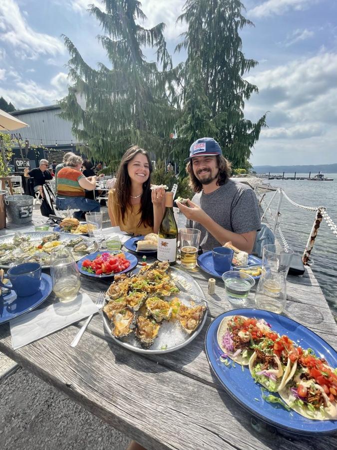 Ali and Sig at a waterfront table in the Pacific Northwest with oysters, tacos and wine