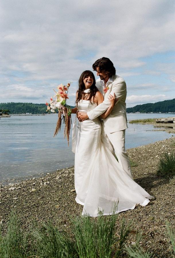 Ali and Sig laughing on the shoreline on their wedding day
